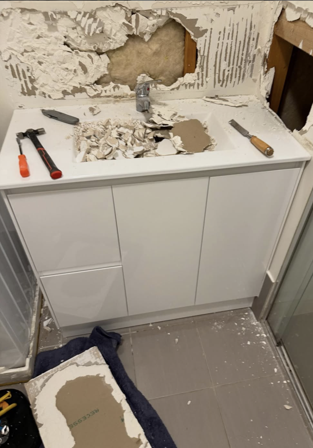 Damaged wall opened up behind the vanity